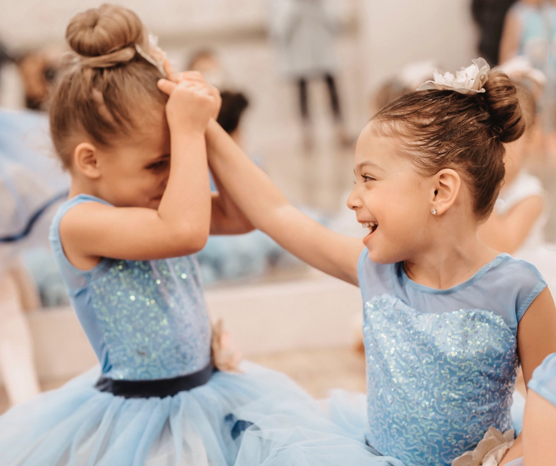 two little girls with light blue ballet costumes smiling and playing
